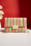 Striped handbag with a gold chain on a white surface against a red background