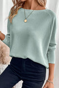 Person wearing a light green sweater and dark pants with a neutral background
