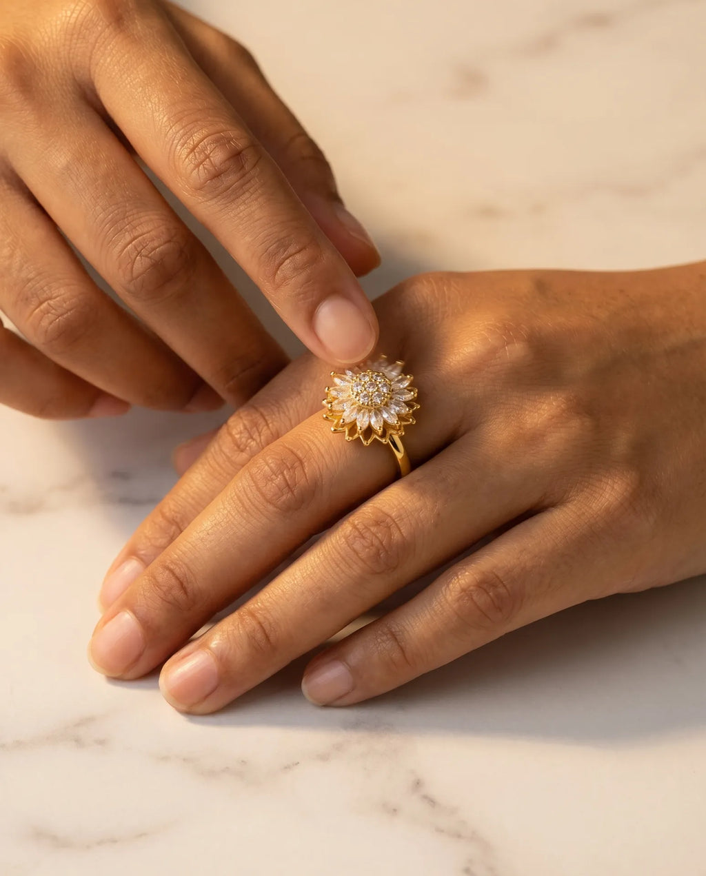 Sunflower Rotation Ring in gold — worn on hand, spinning mechanism close-up on marble surface