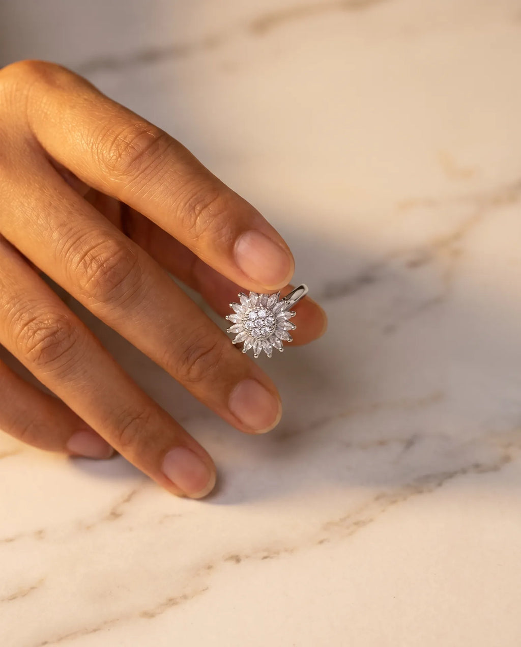 Sunflower Rotation Ring in silver — worn on hand, sunflower detail on warm marble surface